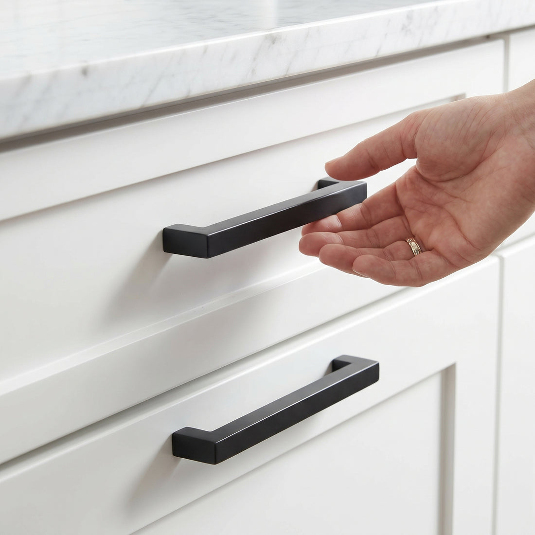 Cauldham matte black square cabinet pulls installed on white shaker drawers in a modern kitchen
